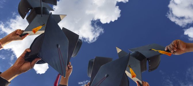 The students holding a shot of graduation cap by their hand in a bright sky during ceremony success graduates at the University, Concept of Successful Education in Hight School,Congratulated Degree